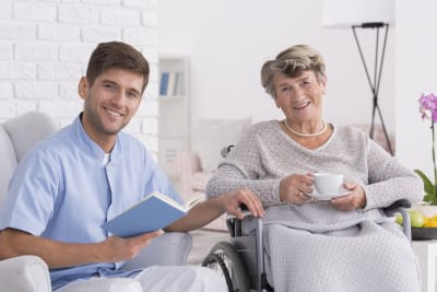 senior woman on wheelchair with young male assistant