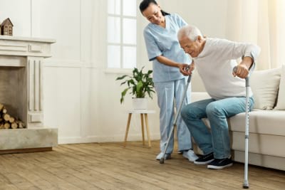 caregiver assiting senior holding walking sticks to walk